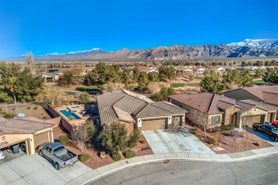Aerial view of a quiet residential street of tile-roofed homes with snow-capped mountains beyond