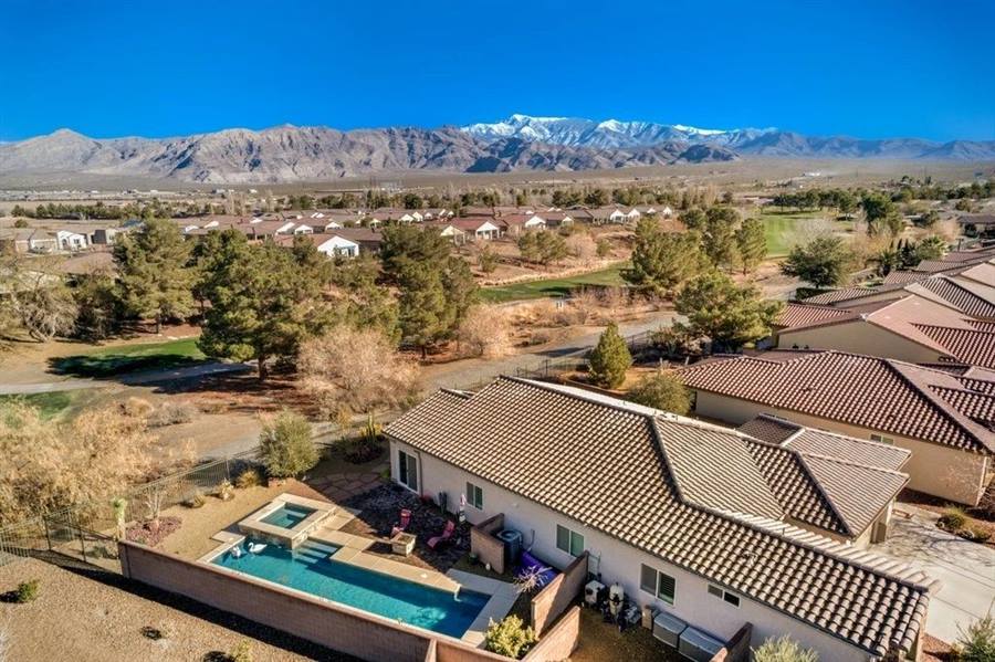 Aerial view of a tile-roofed home with a backyard pool and spa backing onto the golf course