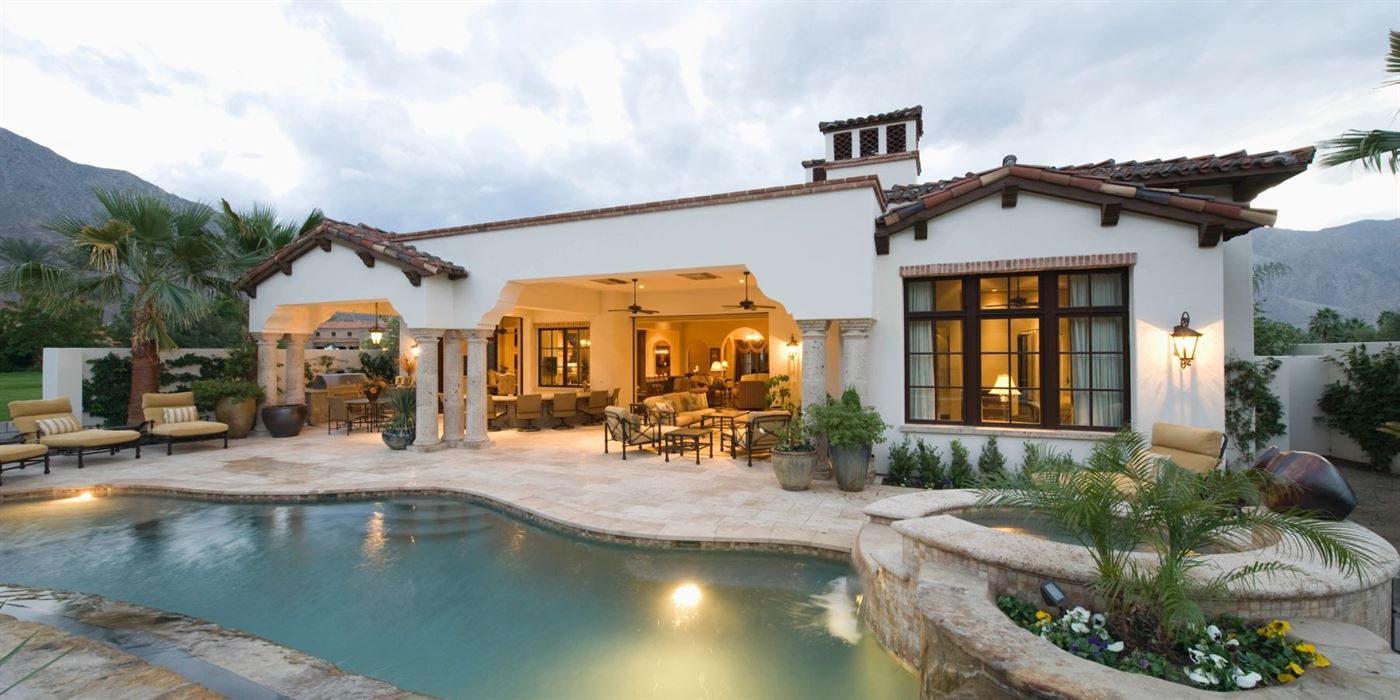 Southwestern-style home at dusk with a lit patio and pool