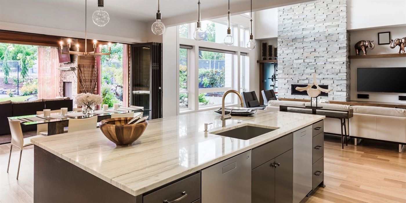 Open-plan kitchen with a marble island opening onto a living room and garden
