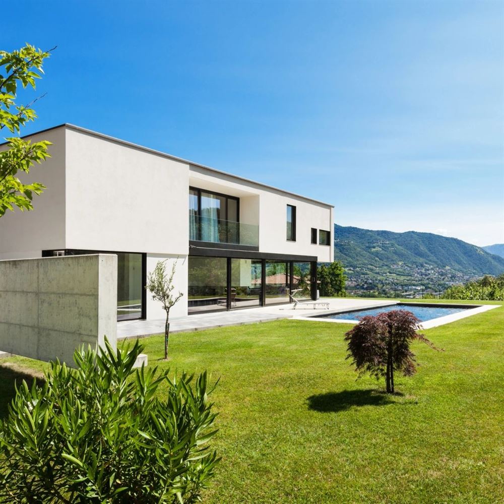 Modern white home with a lawn and lap pool overlooking a valley