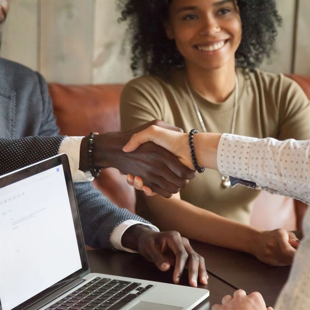 Two people shaking hands across a table after signing paperwork